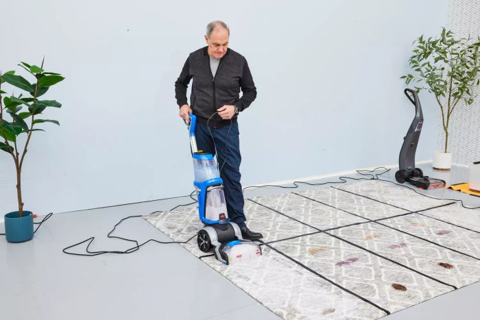 An individual using a Bissell ProHeat 2X Revolution Pet Carpet Cleaner 35799 on a carpet with various stains
