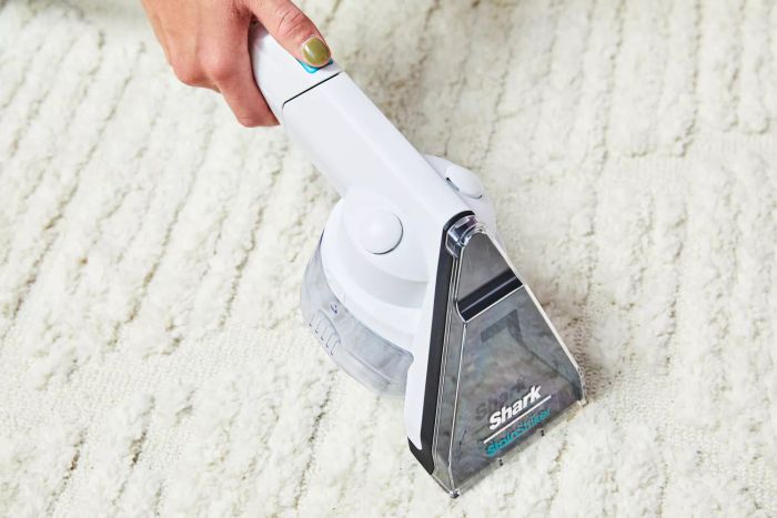 A detailed view of the handheld section of the Shark CarpetXpert with Stainstrike Upright Deep Carpet Cleaner in use