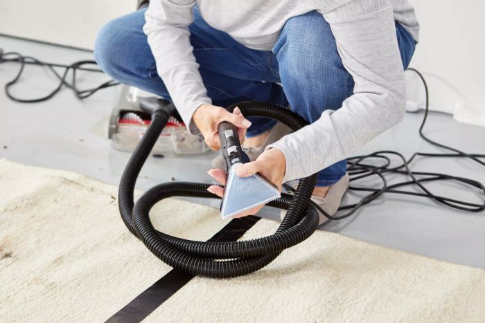 An individual holding the nozzle of the Hoover PowerDash Pet Advanced Carpet Cleaner