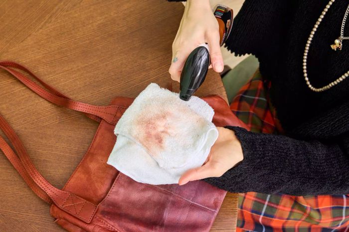 An individual sprays Weiman Leather Cleaner and Conditioner Spray onto a cloth