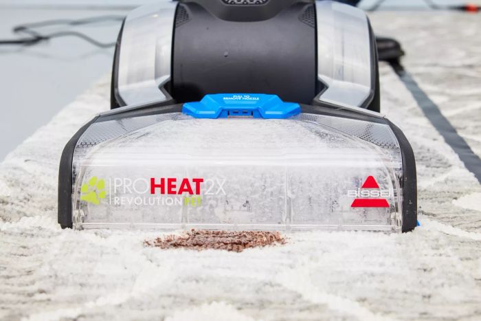 A close-up view of the front of a Bissell ProHeat 2X Revolution Pet Carpet Cleaner 35799 preparing to remove a stain from a carpet