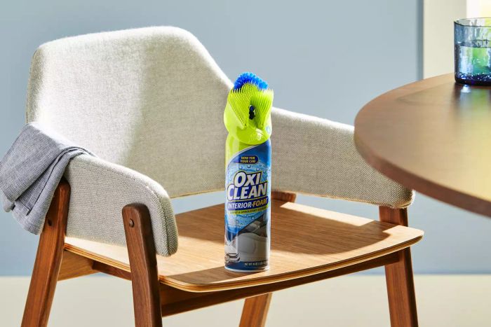 A bottle of OxiClean Total Interior Carpet & Upholstery Cleaner placed on a dining room chair