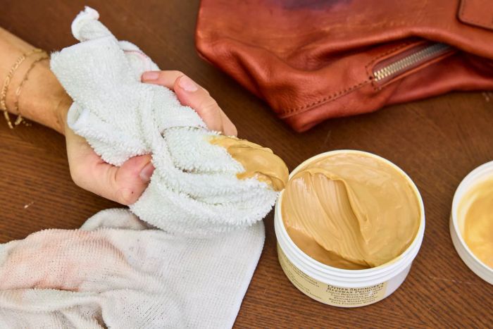 An individual applies Skidmore's Original Leather Cream to a cloth