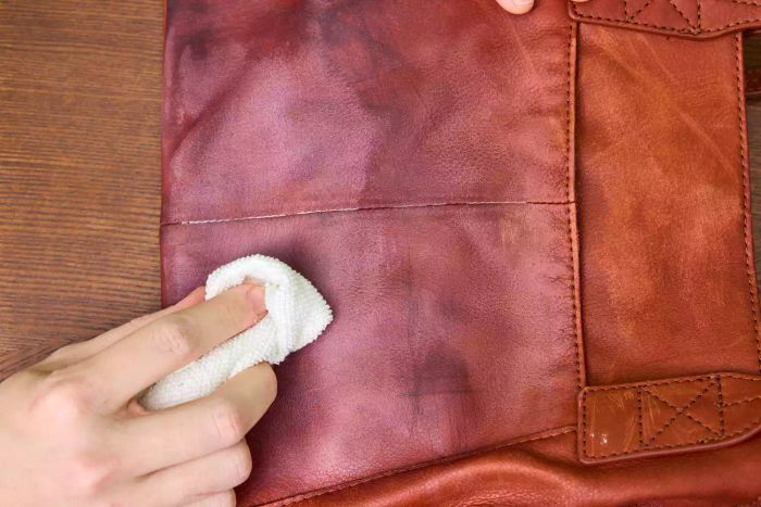 A person works Leather CPR 2-in-1 Leather Cleaner & Leather Conditioner into a leather bag