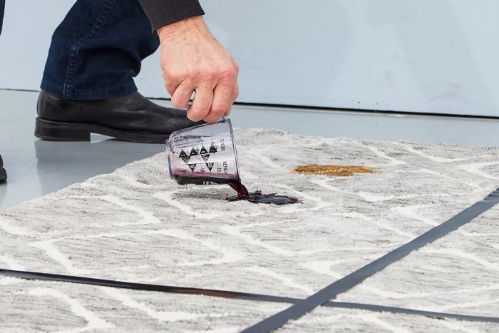 An individual pouring wine onto a rug