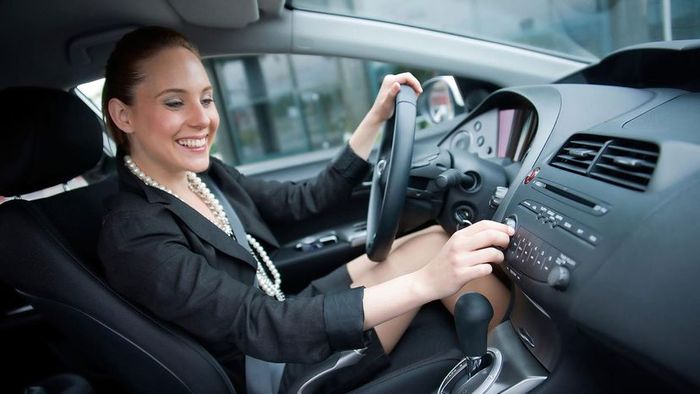 a woman adjusting the radio in her car