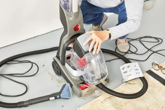 A person disassembling the Hoover PowerDash Pet Advanced Carpet Cleaner