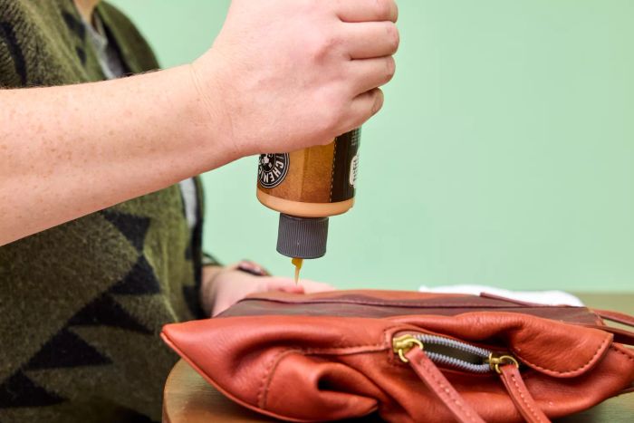 Someone applies the Chemical Guys Leather Cleaner and Conditioner Complete Leather Care to a leather bag