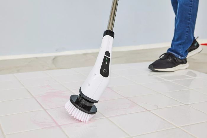 A person cleans white tile using a Losuy Electric Spin Scrubber