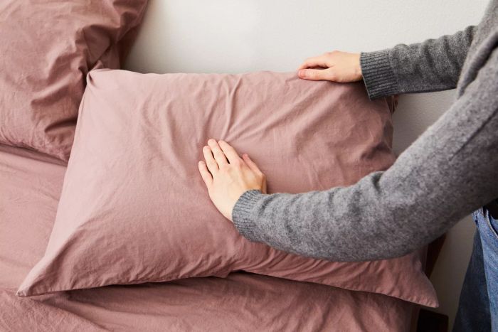 Person feeling the pillow covered with a pillowcase from the Parachute Brushed Cotton Sheet Set