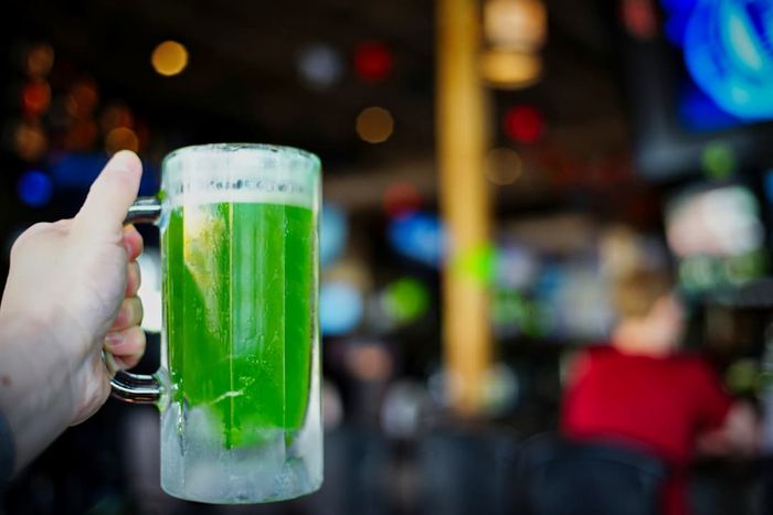 A person holding a pitcher filled with green beer