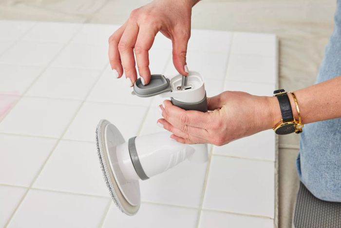 A person holds an IEZFIX Electric Spin Scrubber, showing the charging port