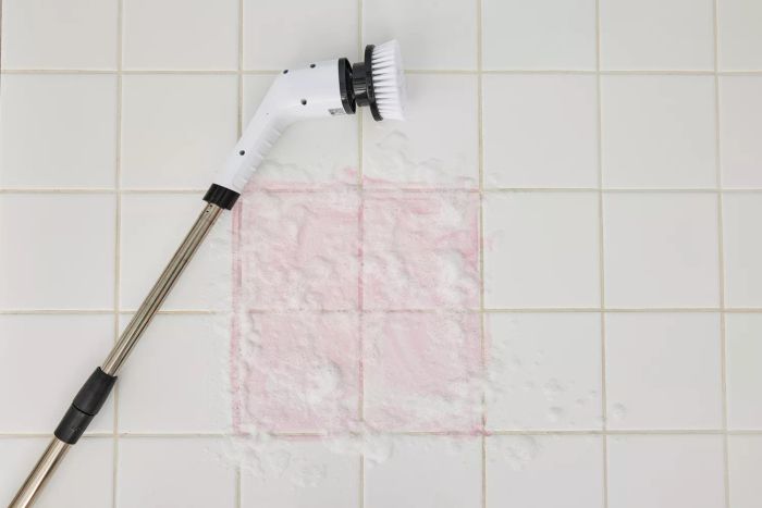 A Losuy Electric Spin Scrubber lies on its side on white, suds-covered tile
