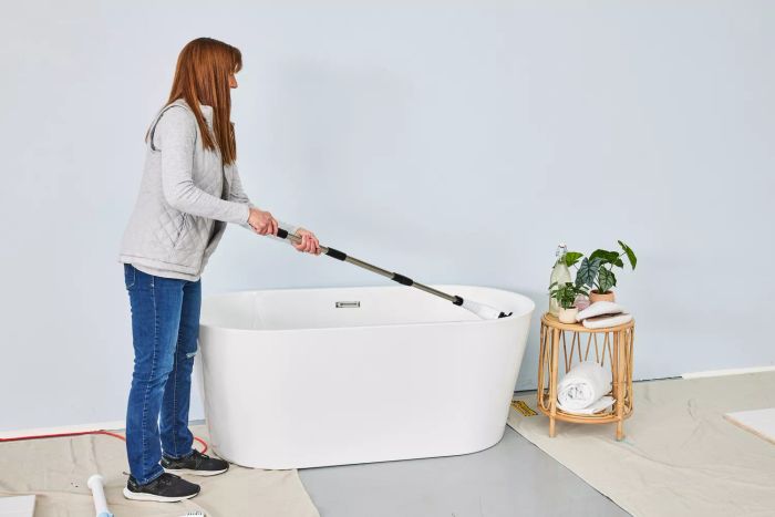A person cleans a white bathtub using a Losuy Electric Spin Scrubber