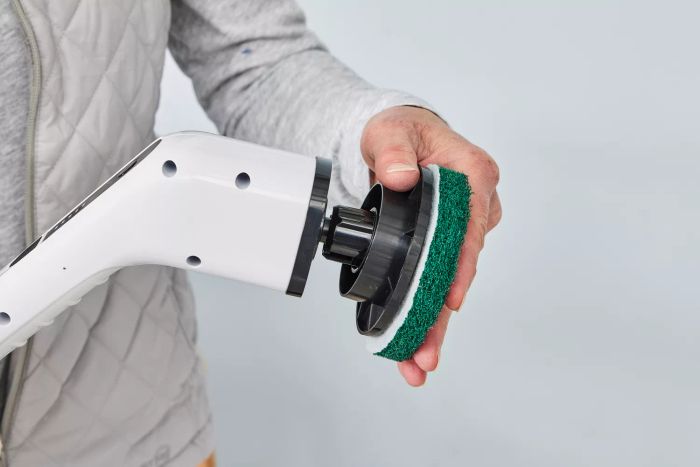 A close-up of a person holding a Losuy Electric Spin Scrubber