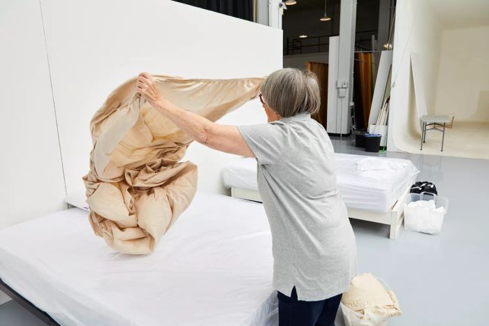 Individual spreading out the Lands' End 400 Thread Count Premium Supima Cotton No Iron Sateen Bed Sheet Set on a bed