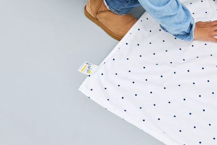 Close-up of a person feeling the texture of a sheet from the California Design Den Cotton Sateen Sheet Set