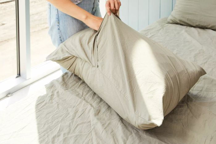 Person inserting a pillow into a pillowcase from the Parachute Percale Venice Set