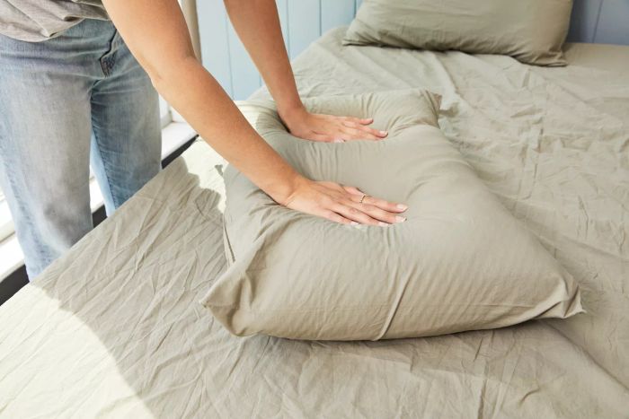 Individual pressing down on a pillow made with the Parachute Percale Venice Set