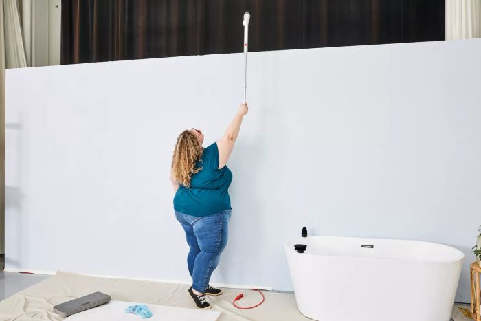 A person evaluates the reach of a HattyRoom Rechargeable Cordless Electric Spin Scrubber