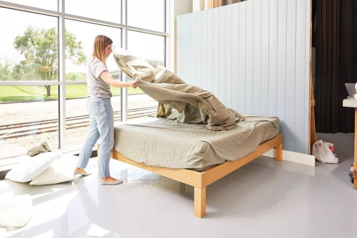 Individual spreading the Parachute Percale Sheet Set onto a bed