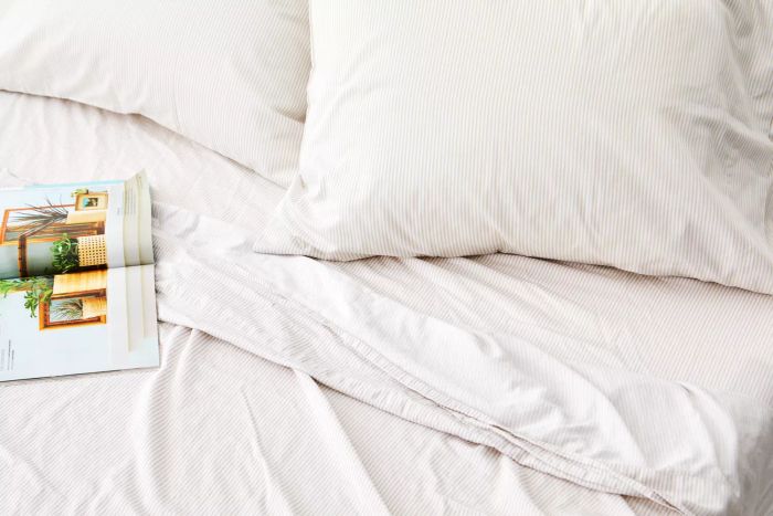 Close-up of a bed dressed with The Citizenry Organic Resort Cotton Sheet Set, featuring a magazine nearby