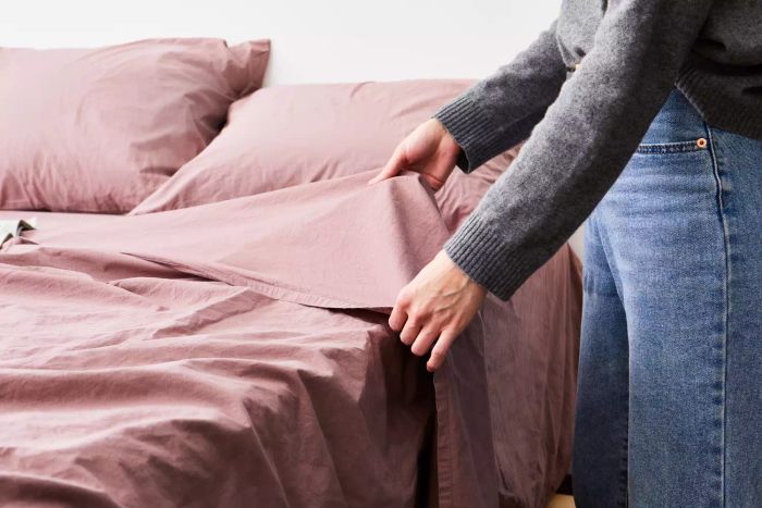 Hands arranging the bed with the Parachute Brushed Cotton Sheet Set