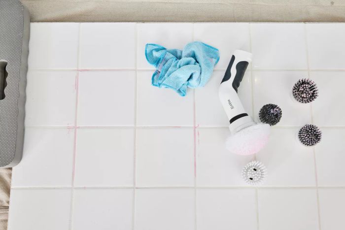 A Klever Electric Spin Scrubber with 8 Brushes lies on its side on white tile