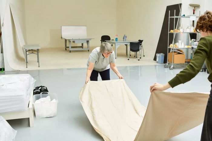 Two individuals holding the ends of the Lands' End 400 Thread Count Premium Supima Cotton No Iron Sateen Bed Sheet Set