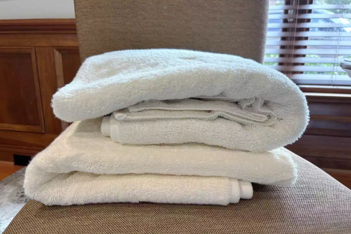 Two folded Italic Serene Ultraplush Australian Cotton Towels displayed on a chair