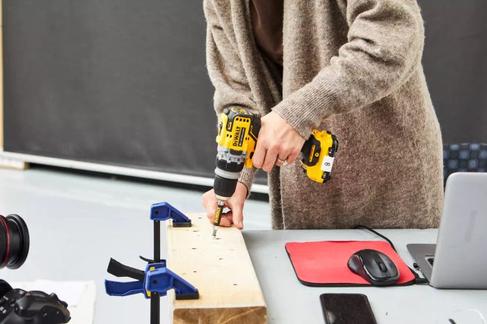 A person tightening a screw on a wooden piece using the DeWalt Screwdriver Bit Set With Tough Case attached to a drill machine