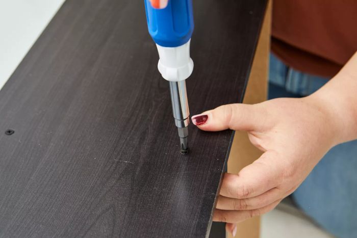 A person using the Lenox 9-in-1 Rubber Handle Multi-Bit Screwdriver to tighten a screw on wood