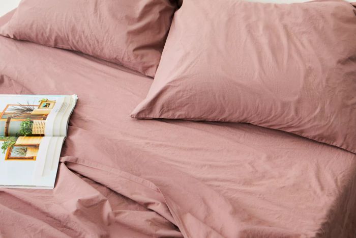 Close-up of a bed dressed with the Parachute Brushed Cotton Sheet Set, featuring a magazine placed on the side