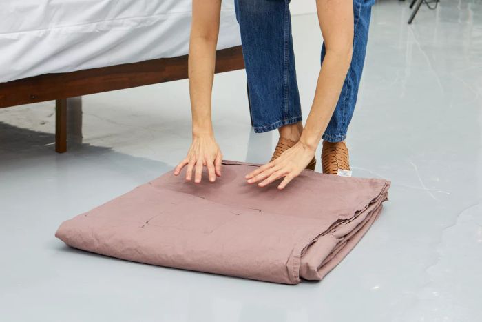 Individual lifting the folded Parachute Brushed Cotton Sheet Set from the floor