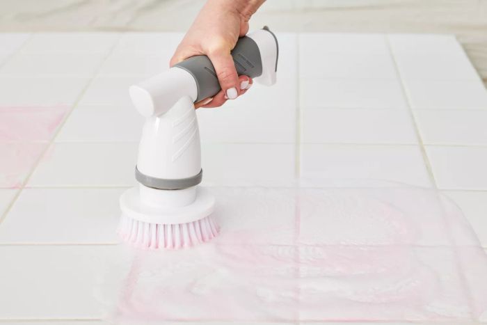 A person cleans white tile using an IEZFIX Electric Spin Scrubber