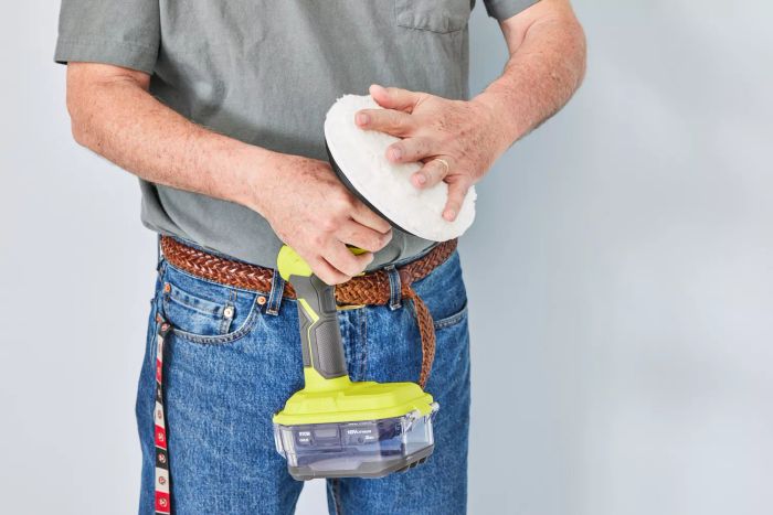 A person attaches a scrubbing pad to a Ryobi One+ 18V Cordless Compact Power Scrubber