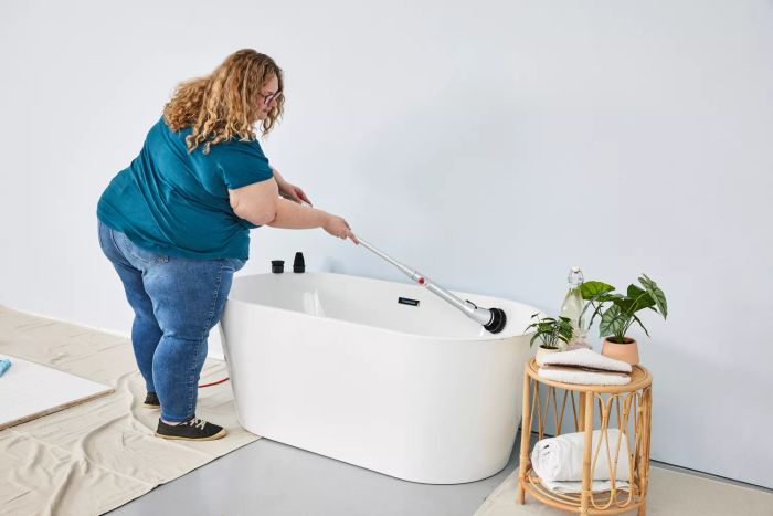 A person cleans a white bathtub using a HattyRoom Rechargeable Cordless Electric Spin Scrubber