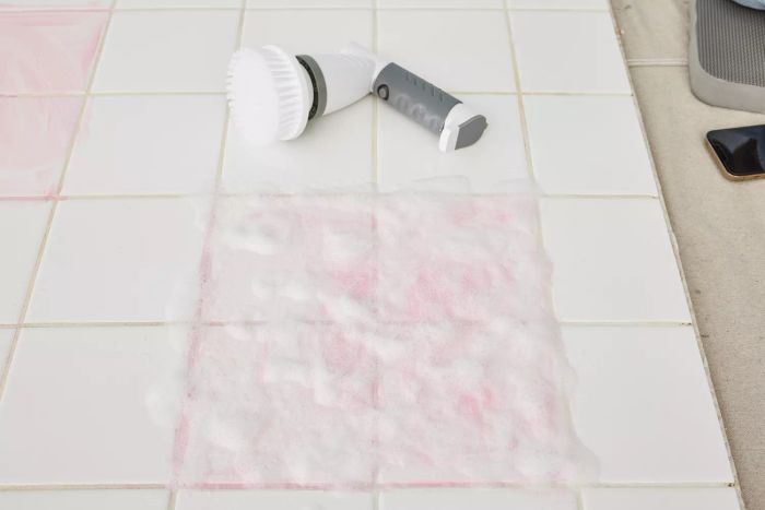 An IEZFIX Electric Spin Scrubber rests on white tile covered with suds