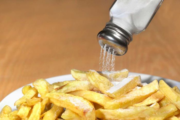 Salt being sprinkled over french fries.