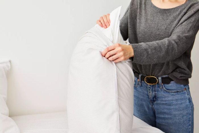 Person placing a pillowcase from The Citizenry Organic Resort Cotton Sheet Set onto a pillow
