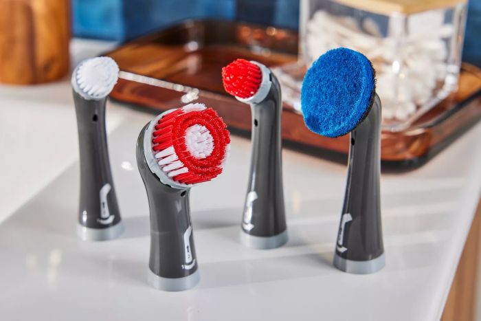 Four attachments for the Rubbermaid Reveal Power Scrubber are arranged on a countertop