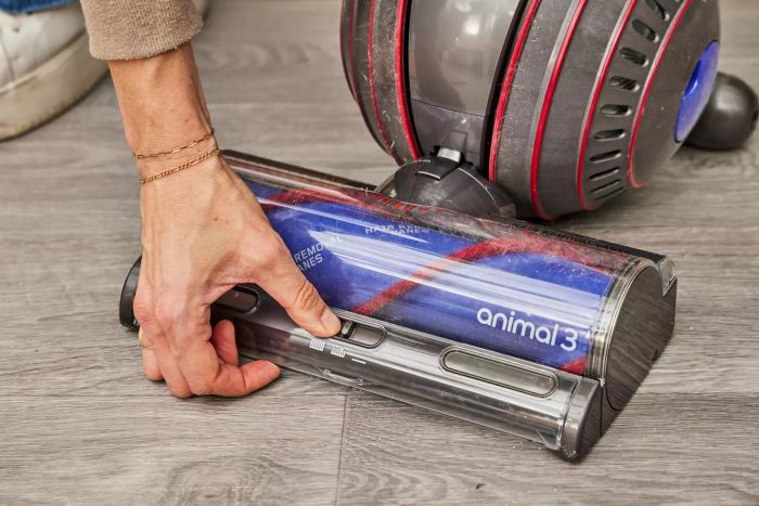 A hand adjusting the switch located at the base of the Dyson Ball Animal 3 Extra