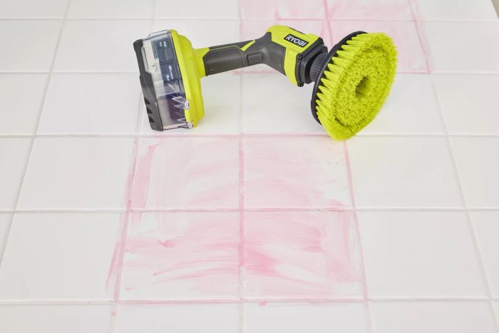 A Ryobi One+ 18V Cordless Compact Power Scrubber lies on white tile stained with red marker