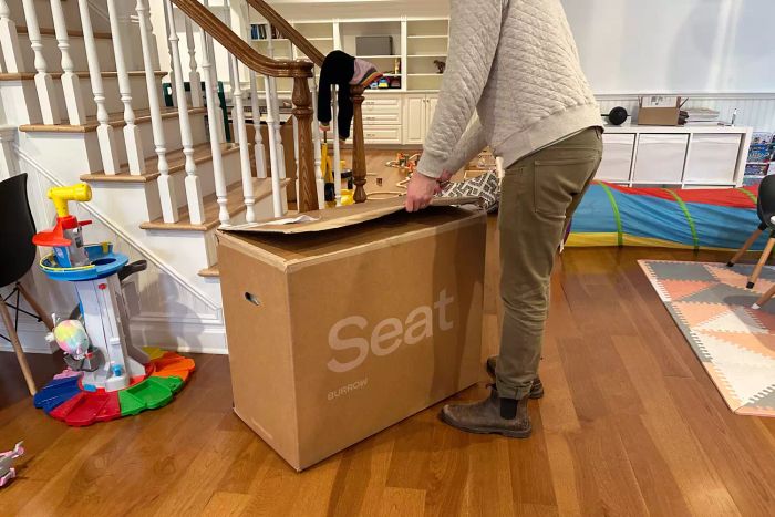 A person unpacking the Burrow Block Nomad Sofa