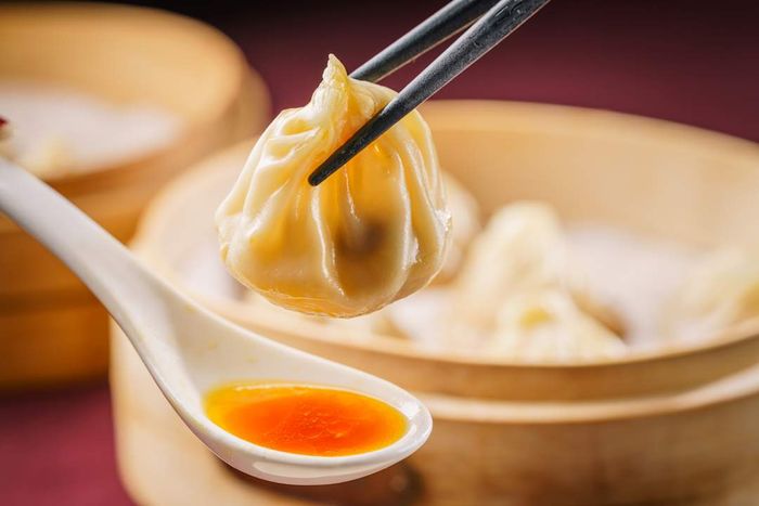 Xiao long bao soup dumpling with broth in a spoon below.