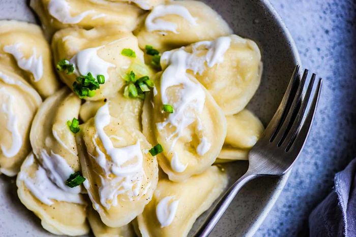 An aerial view of Ukrainian vareniki dumplings filled with potato, served with sour cream and chives
