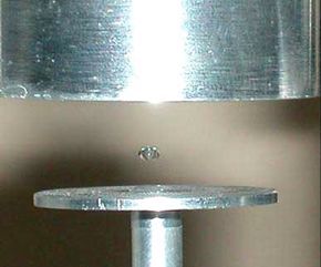 A tiny droplet hovers effortlessly above a metallic surface.