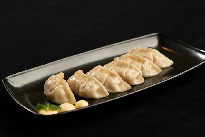Jiaozi dumplings arranged on a black plate atop a dark table.