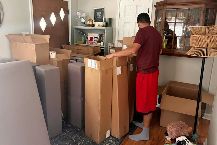 A person unpacking the 7th Avenue 4-Seat Modular Chaise Sectional in their living room