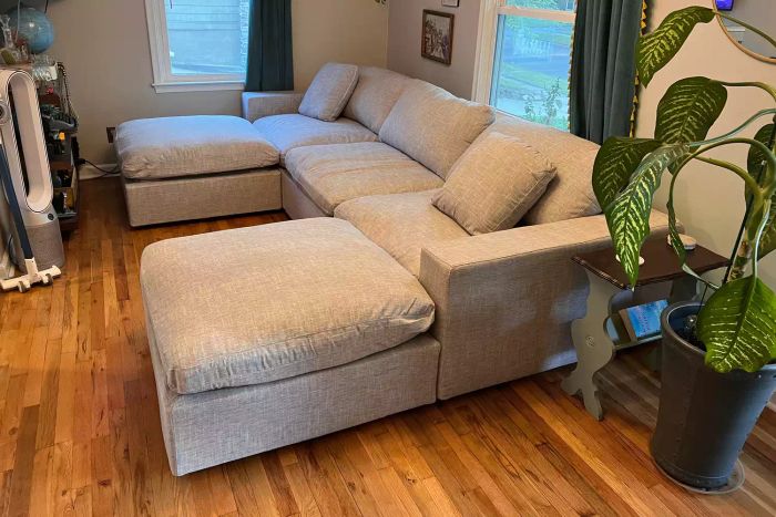 The 7th Avenue 4-Seat Modular Chaise Sectional with Ottoman arranged in a living room near windows and plants